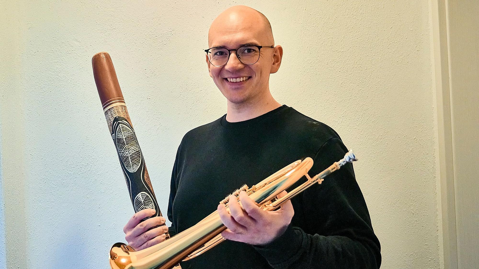 Kreisdirigent Nico Haag posiert mit zwei Instrumenten in den Händen.