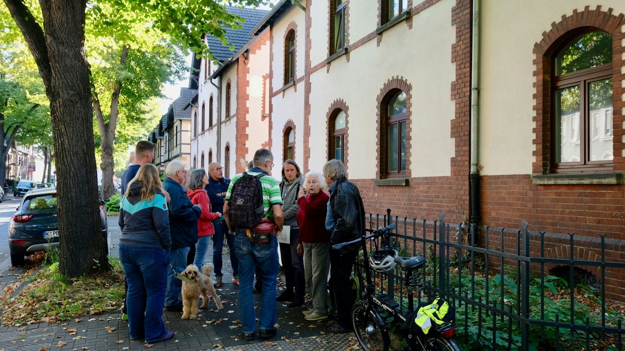 Anwohner und Anwohnerinnen haben sich vor einem Gaswerkhäuschen versammelt, um mit einem Plakat auf den Leerstand aufmerksam zu machen und darüber zu beraten.