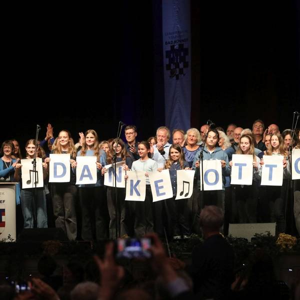 Zwei Chöre auf der Bühne, die in der ersten Reihe auf großen Blättern mit einzelenen Buchstaben „Danke Otto“ zeigen.