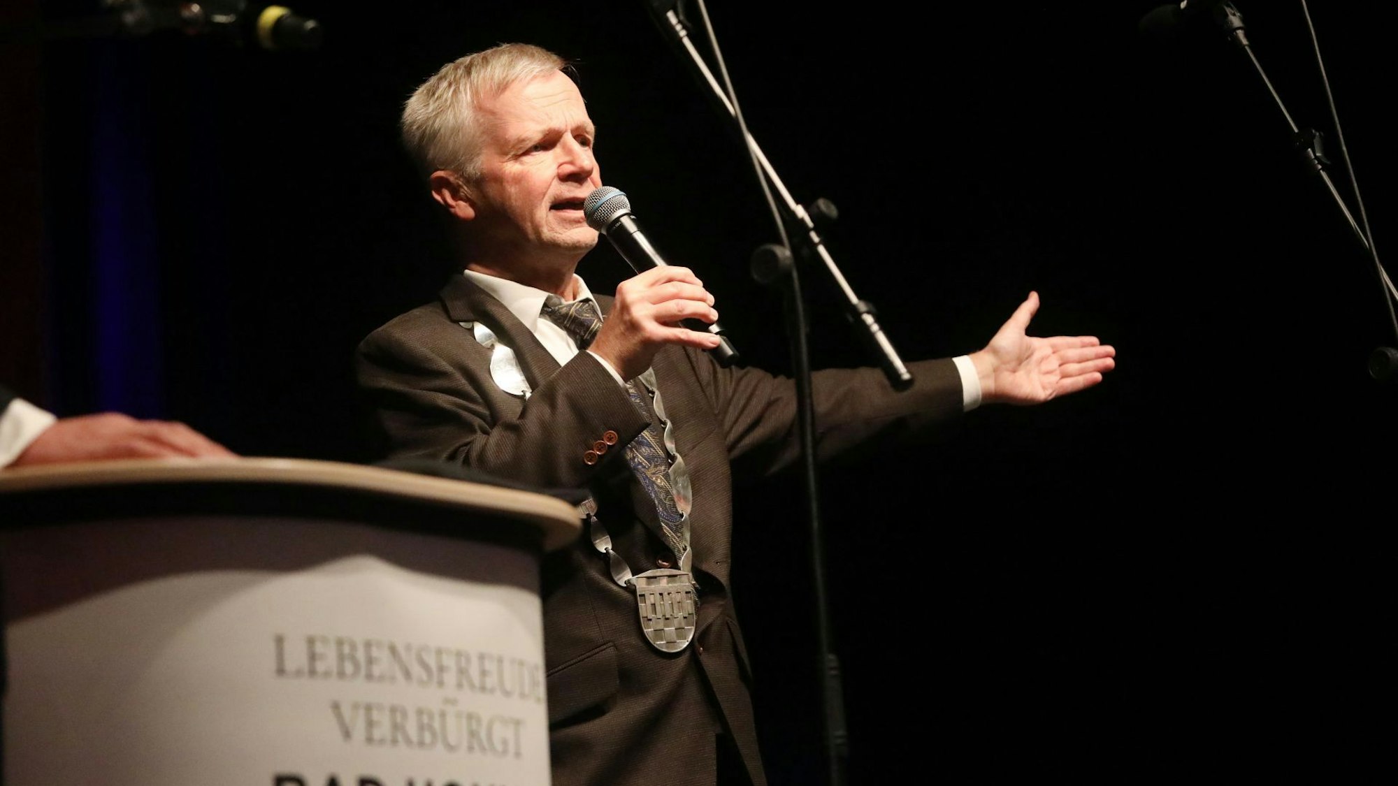 Ein Mann mit Mikrofon und der Amtskette des Bürgermeisters.