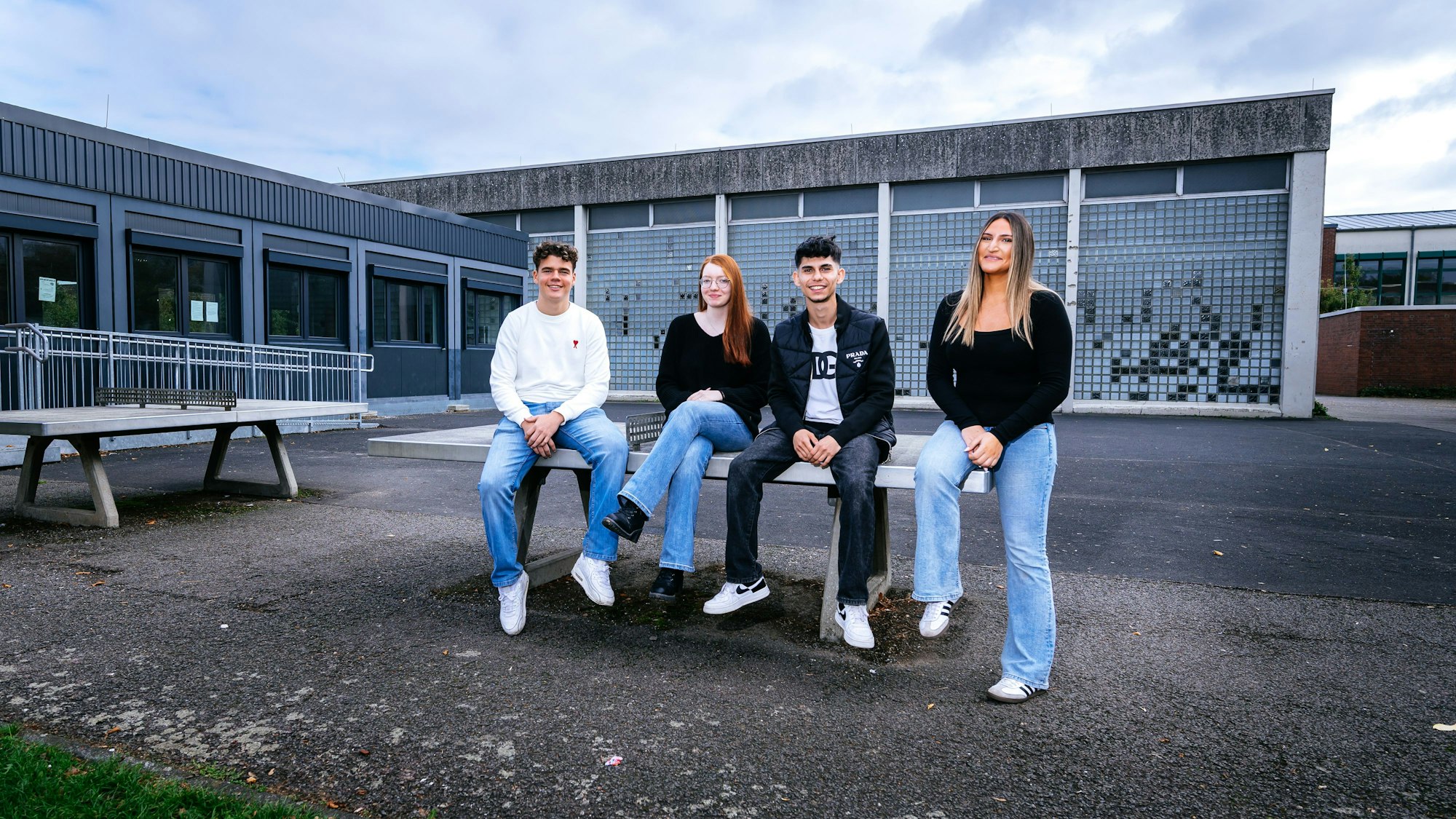 Schülerinnen und Schüler sitzen auf einer Tischtennisplatte.