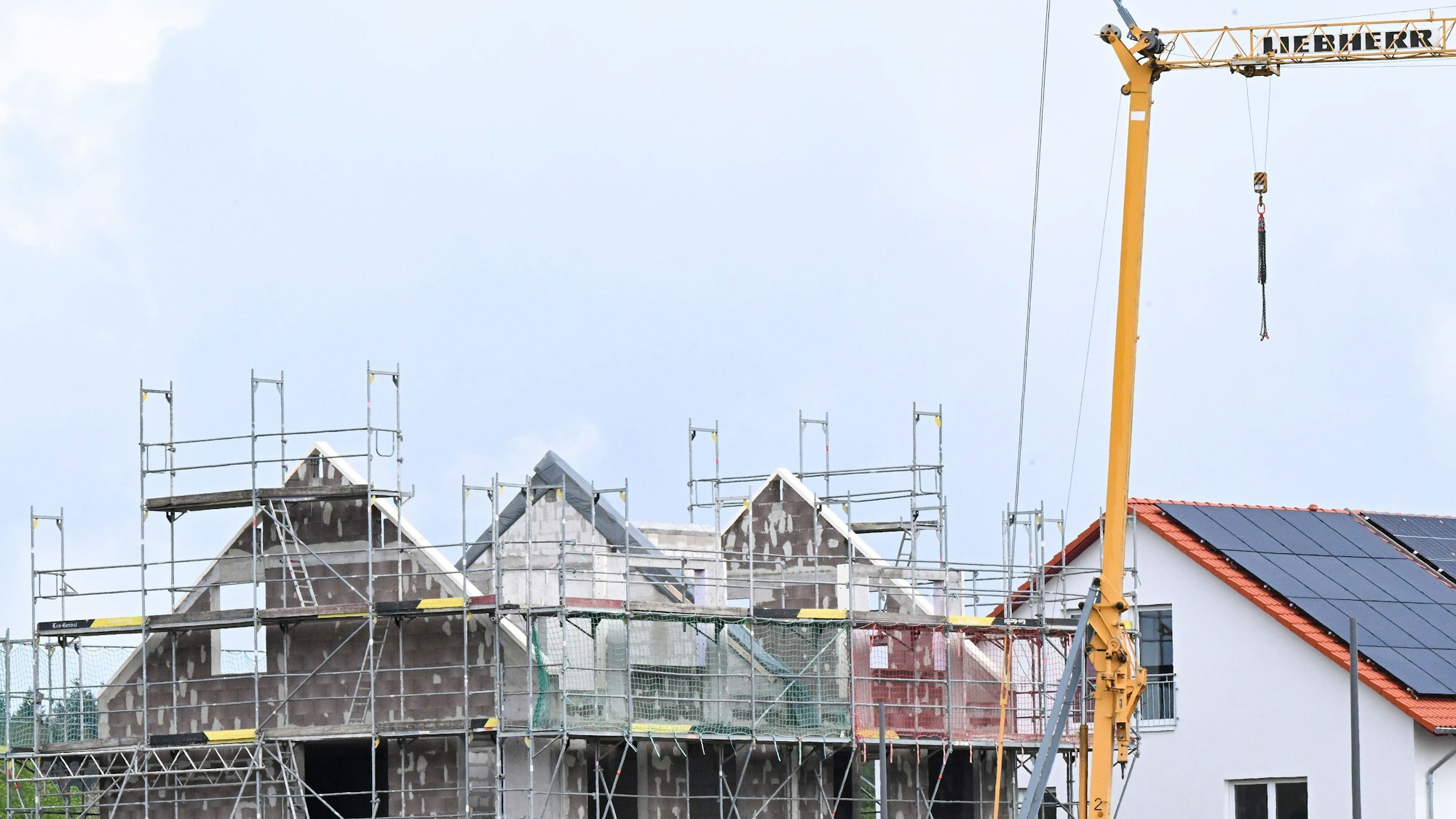 Das Bild zeigt ein im Bau befindliches Haus. Ein Baukran steht davor.