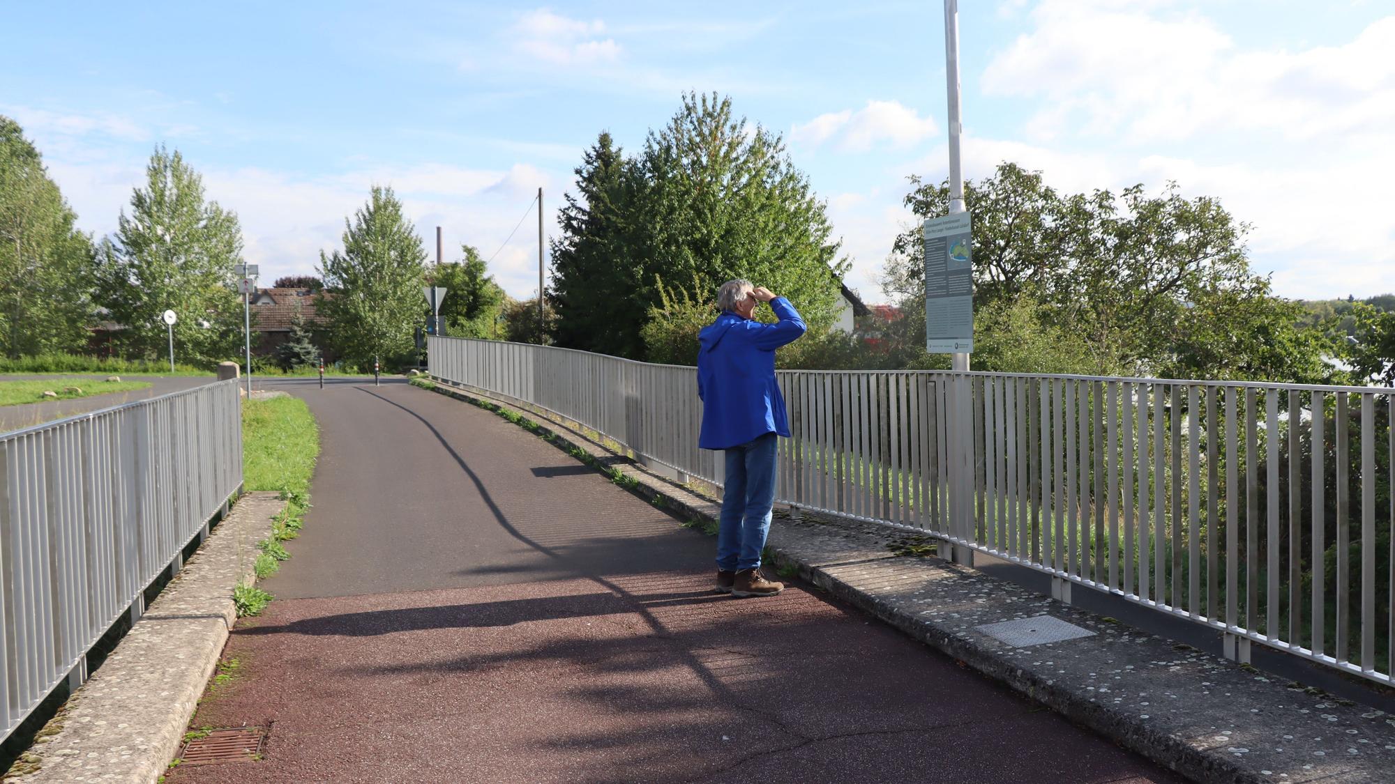 Eine Person steht auf einer Brücke.