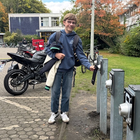 Auf dem Bild ist ein Schüler mit seinem Smartphone zu sehen.