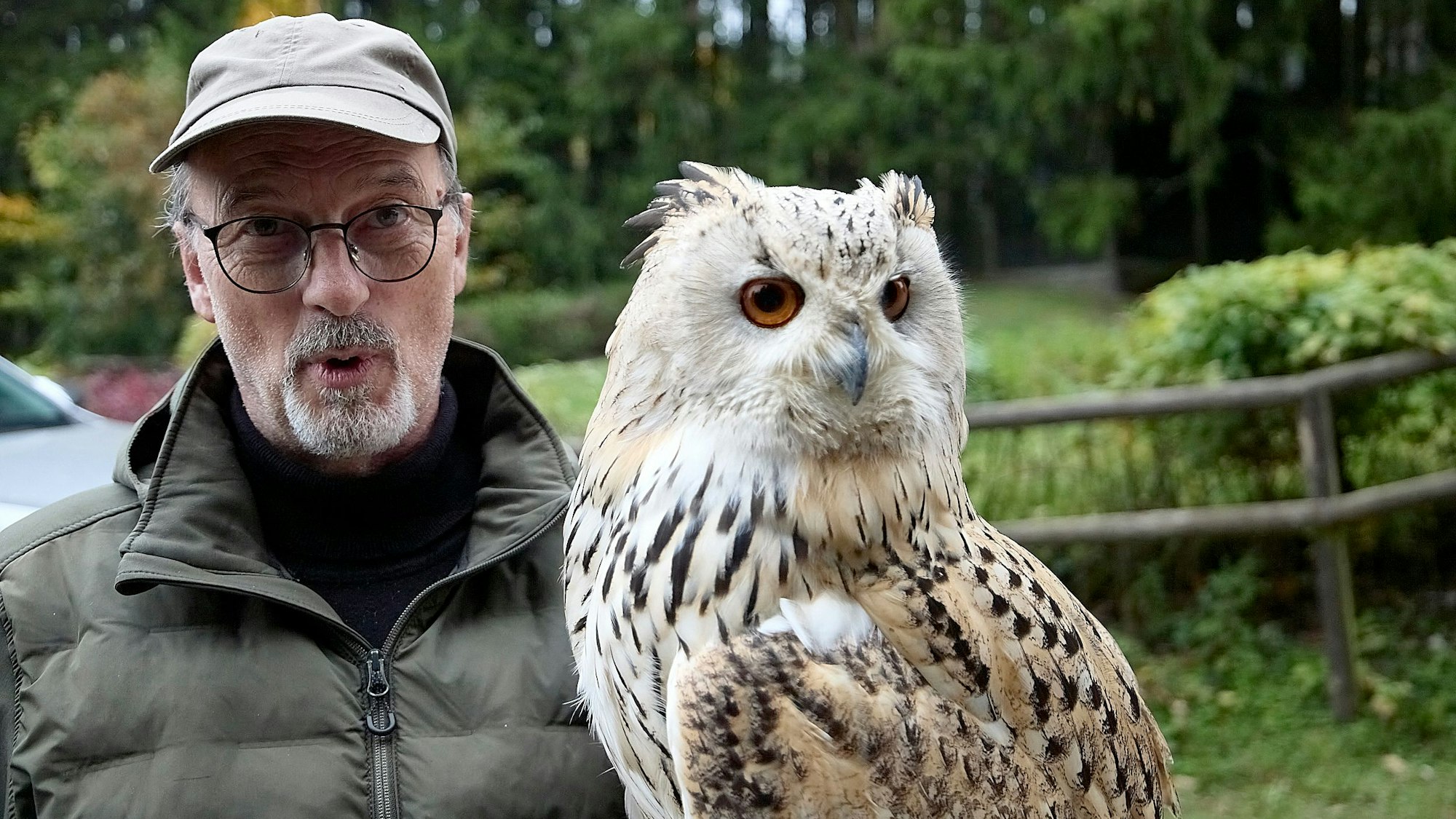 Frank Lens steht neben einem Sibirischen Uhu und schaut in die Kamera.