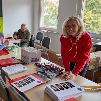 Simone Uhlig, Ines Hermanns, Burkhard Rosenbaum und Andrea Breuer (von links)  befüllen rote Tüten. Auf einem Tisch liegen ausgedruckte Anleitungen und Knicklichter.