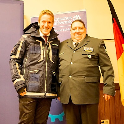 Markus Ramers steht in THW-Einsatzkleidung neben Daniel Schwarzer – beide grinsen.