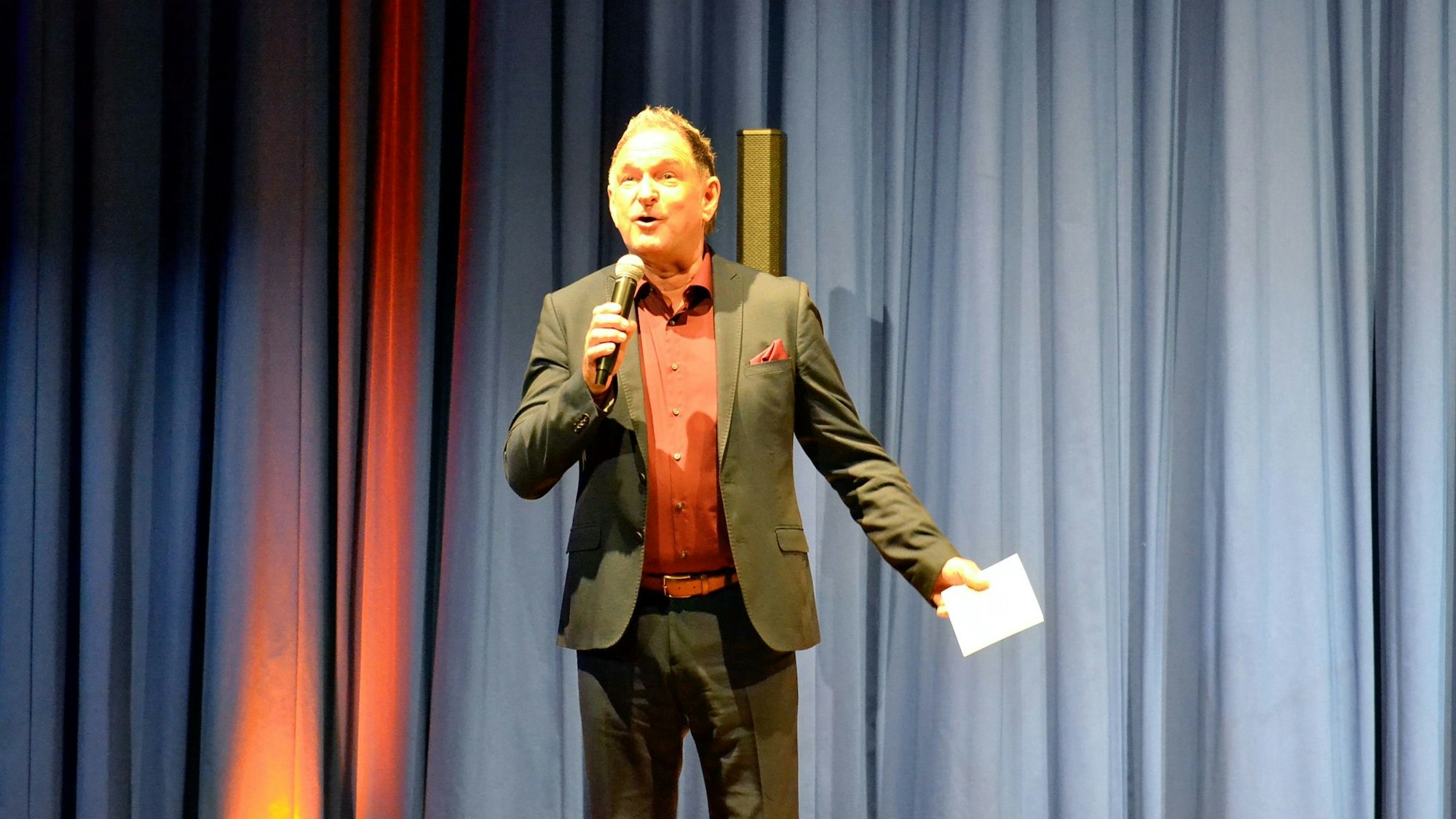 Thomas Gerres trägt einen Anzug mit Einstecktuch und spricht in ein Mikrofon.