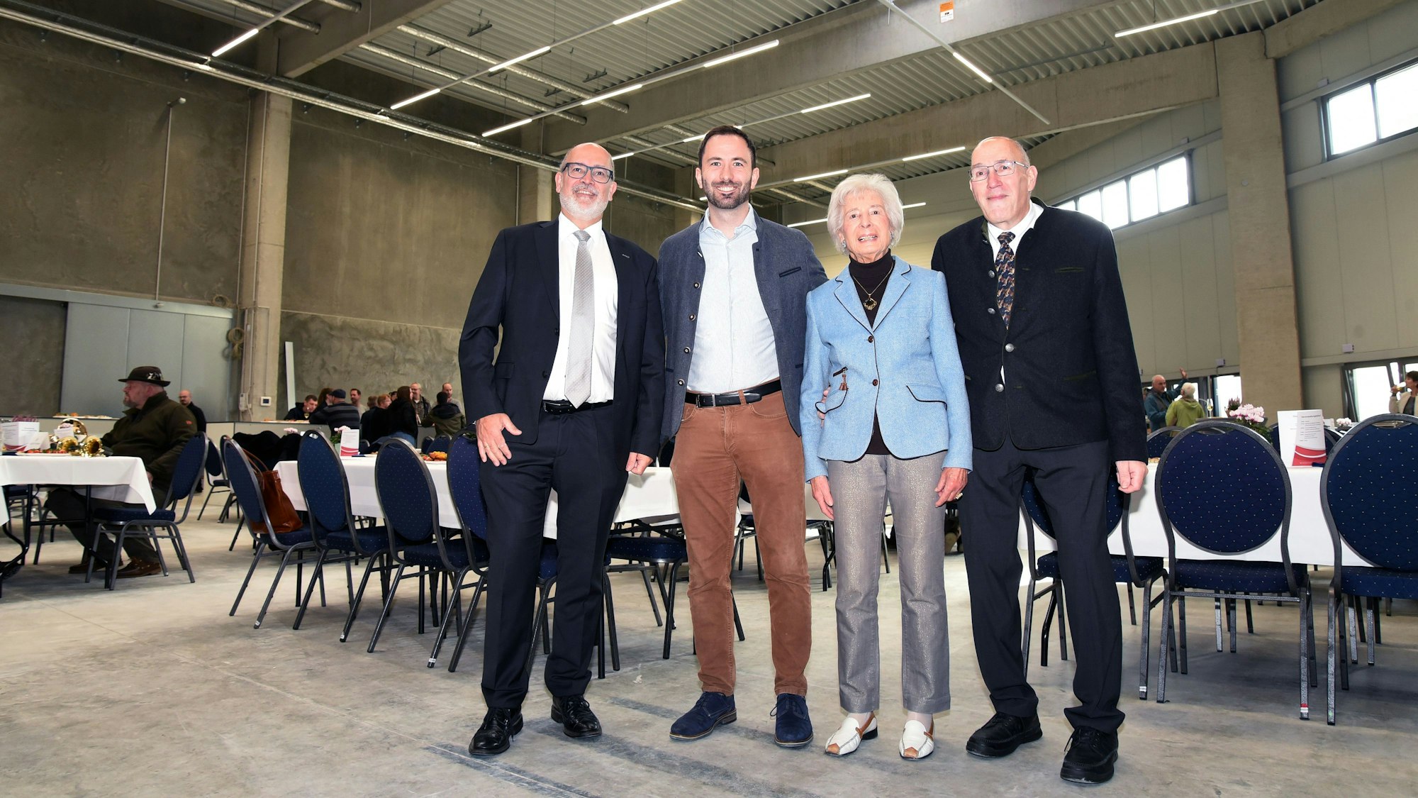 Das Foto zeigt drei Männer und eine Frau in einer großen Halle.