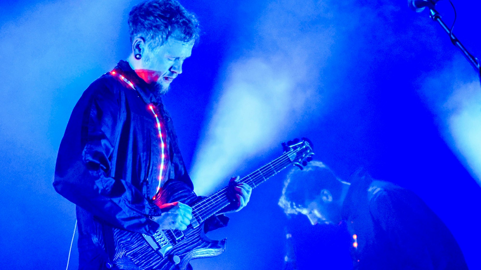 Das Bild zeigt einen Gitarristen und einen weiteren Musiker auf einer Bühne.