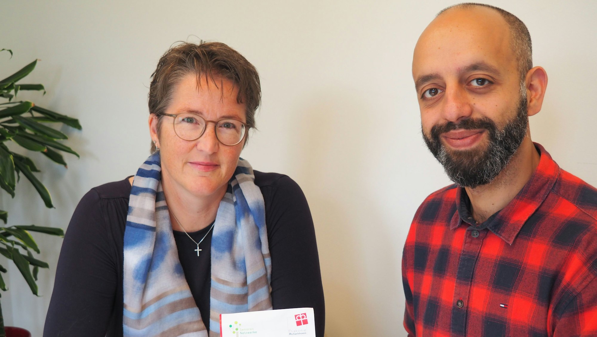 Eine Frau und ein Mann mit Bart sitzen nebeneinander an einem Tisch.