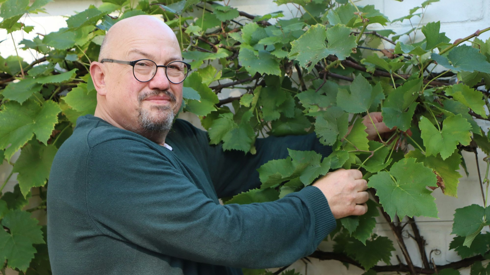 Das Foto zeigt den Feuerwehrchef vor Weinpflanzen in seinem Garten.