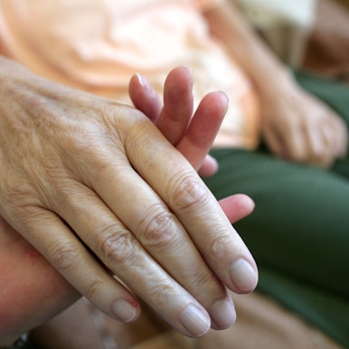 Die Hand einer kranken Frau wird gehalten.