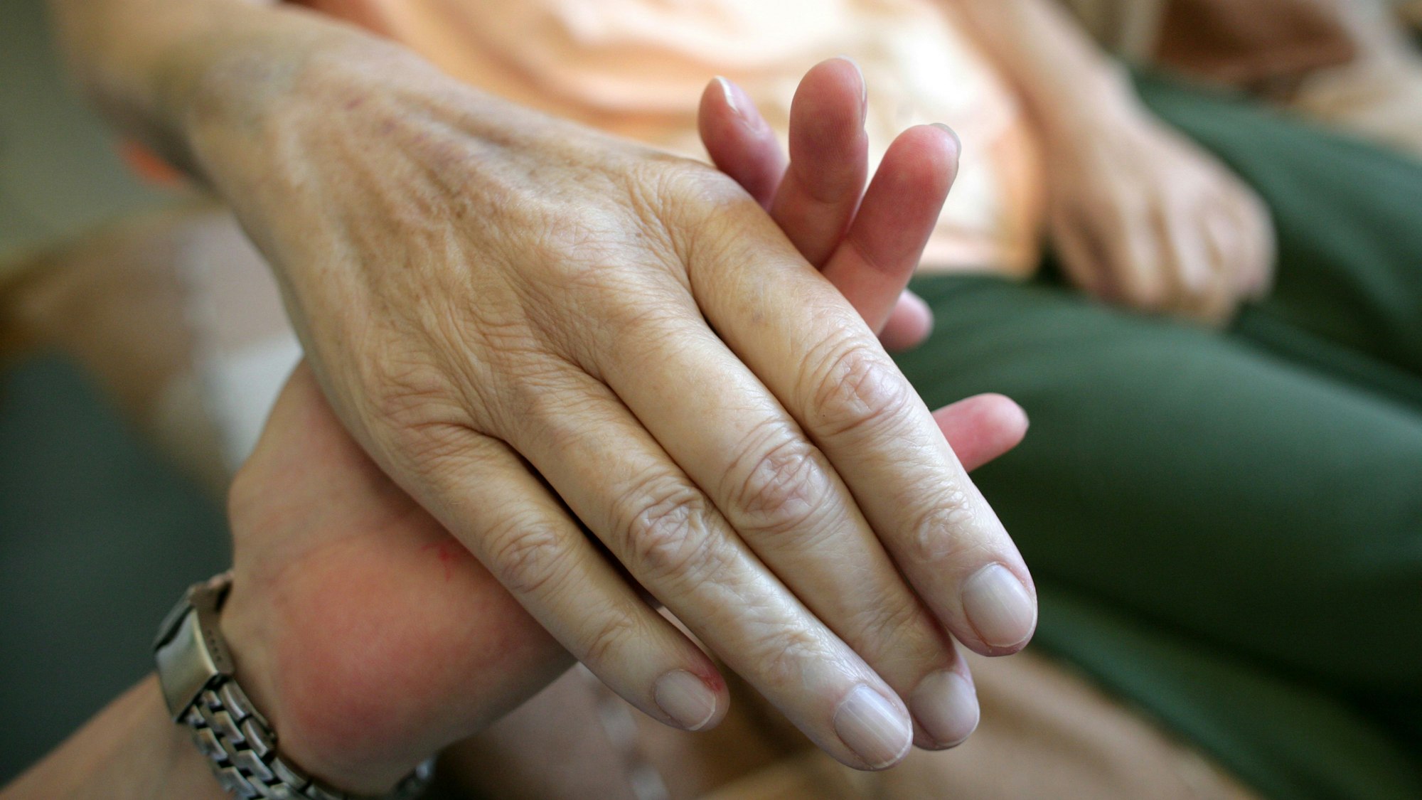 Die Hand einer kranken Frau wird gehalten.