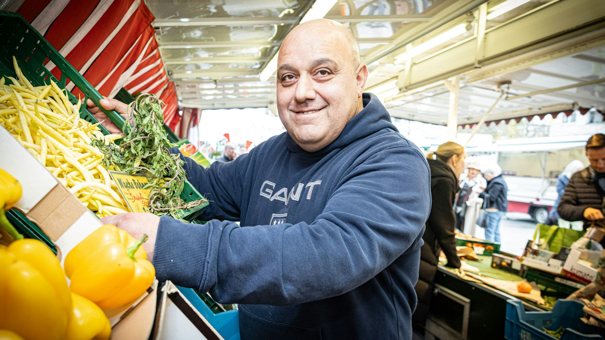 Ein Mann vor Gemüsekisten an einem Wochenmarktstand