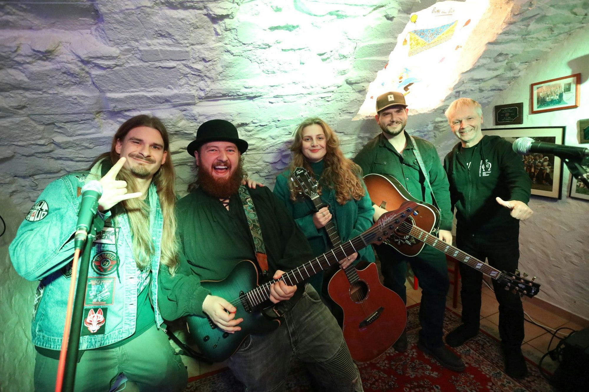 Vier Männer und eine Frau in einem Gewölbekeller, drei von ihnen halten Gitarren in den Händen.