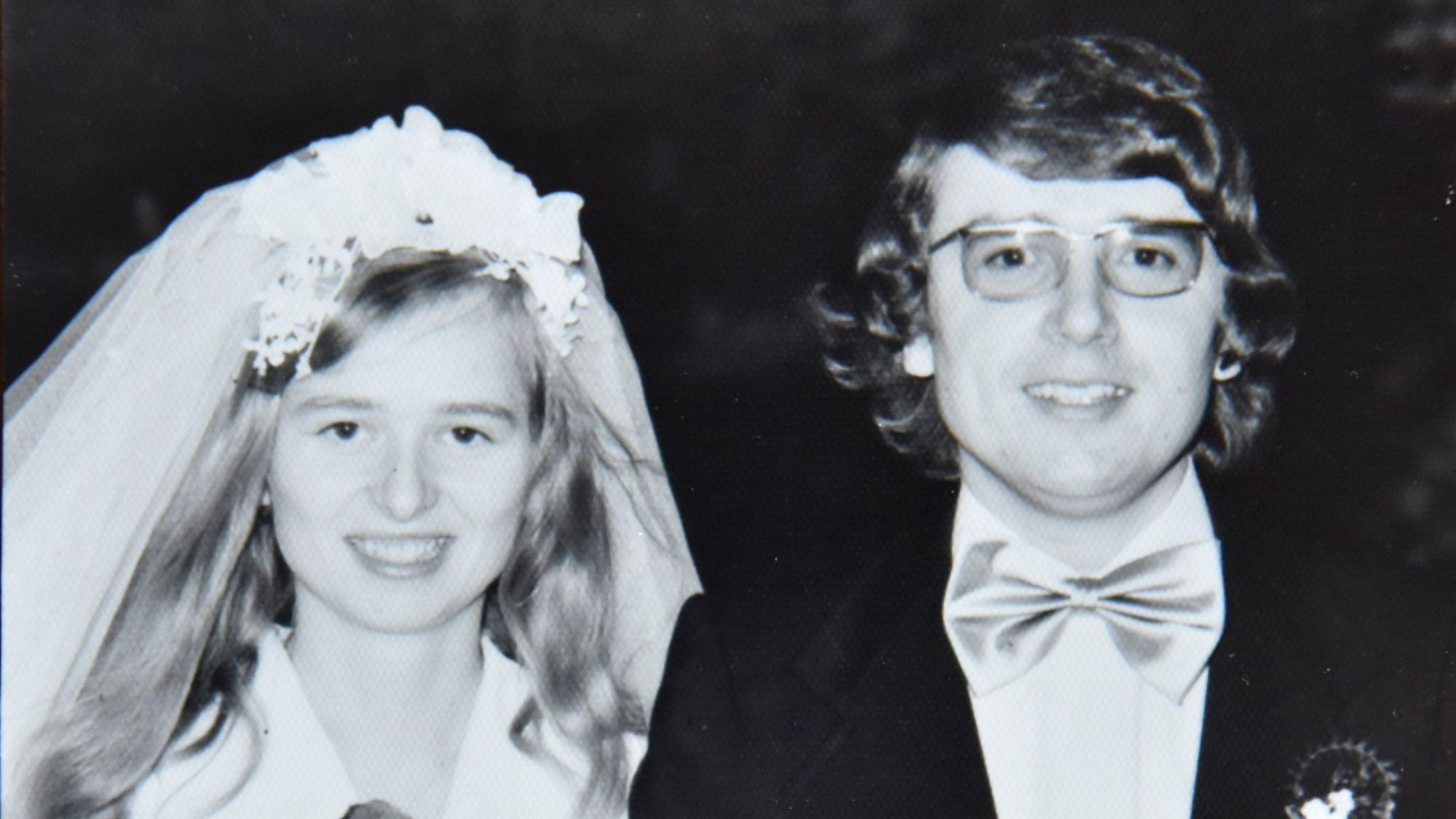 Das Bild zeigt das Paar in Hochzeitskleidung.
