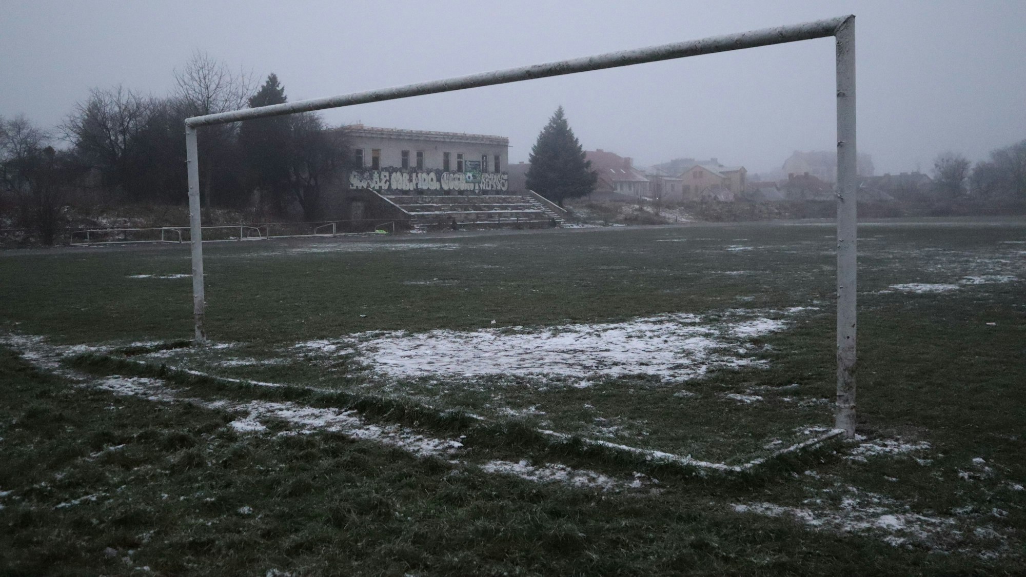 Ein verlassenes Fußballstadion. Im Vordergrund ein Tor ohne Netz.