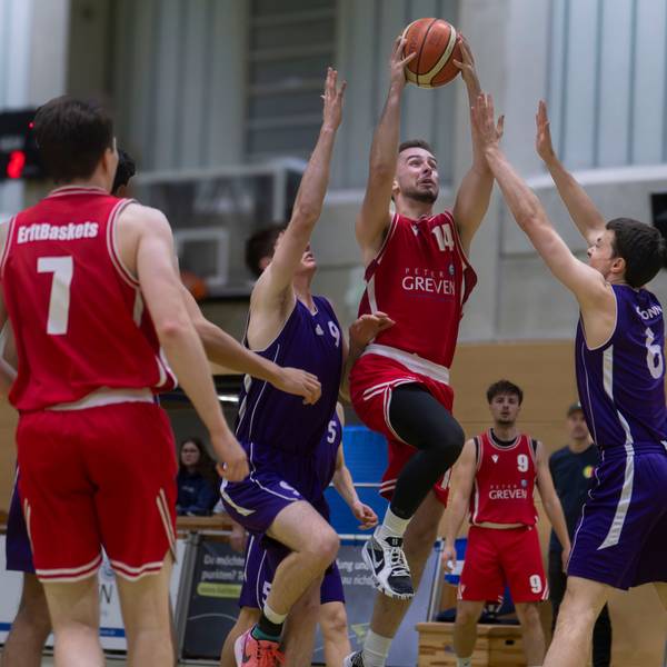 Erftbaskets-Spieler Chris Beier steigt zum Korb hoch und kann auch von zwei Gegenspielern, die die Arme hochreißen, nicht aufgehalten werden.