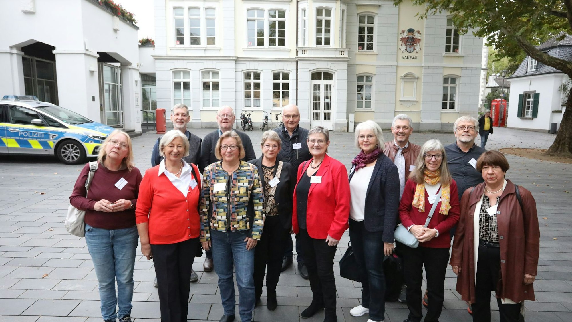 Eine Gruppe von Männern und Frauen auf dem Marktplatz, im Hintergrund das Rathaus von Königswinter.