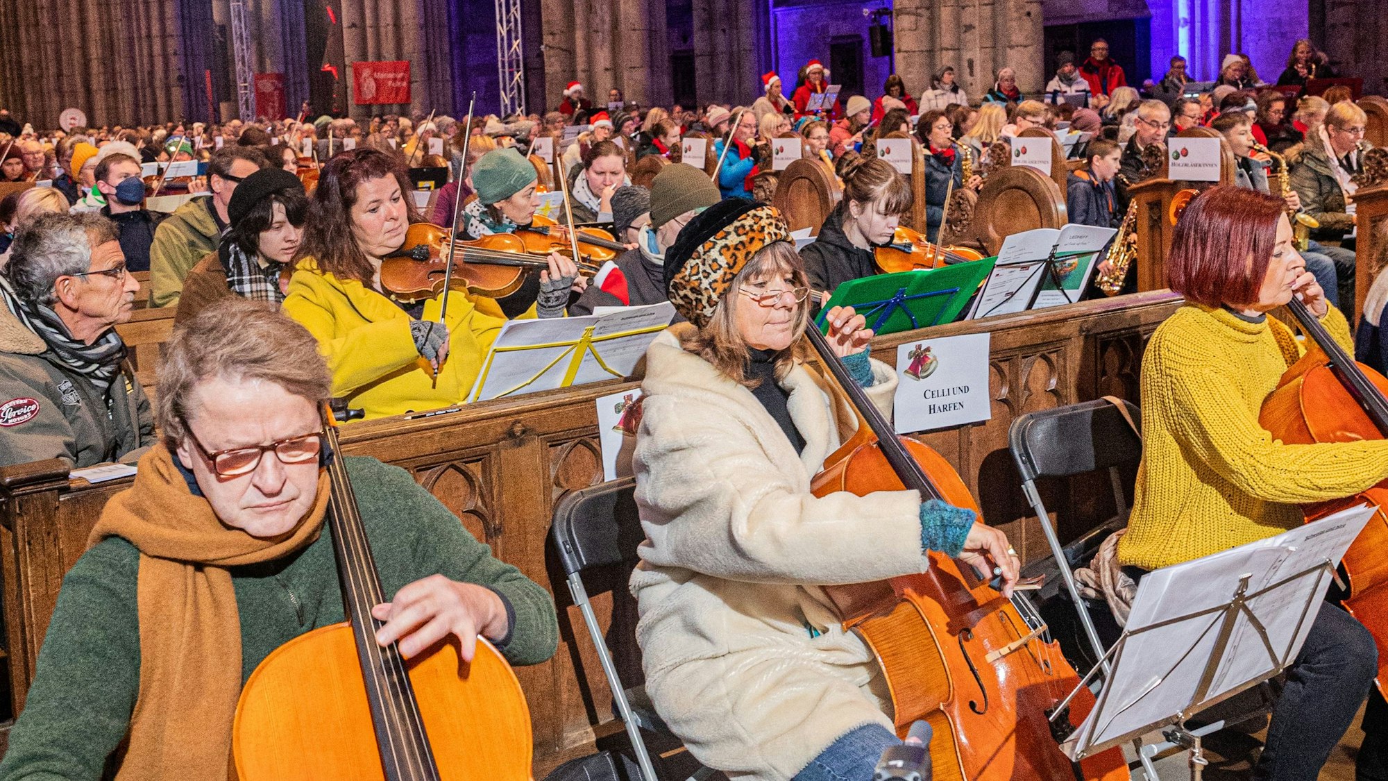 Viele Musizierende an Instrumenten in den Bankreihen des Kölner Doms.