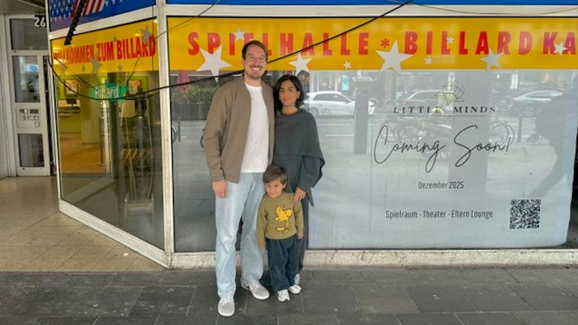 Ein Paar steht mit einem Kleinkind vor der Schaufenster einer Spielhalle.