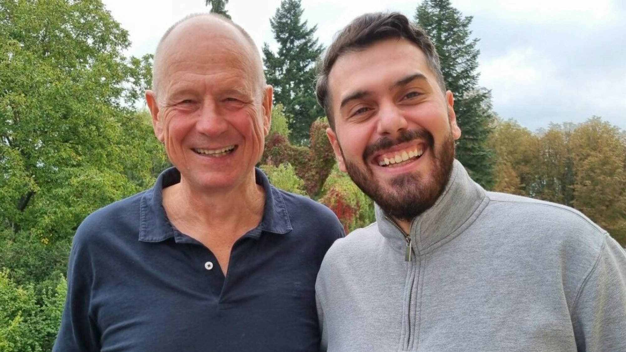 Zwei Männer lachen in eine Kamera.