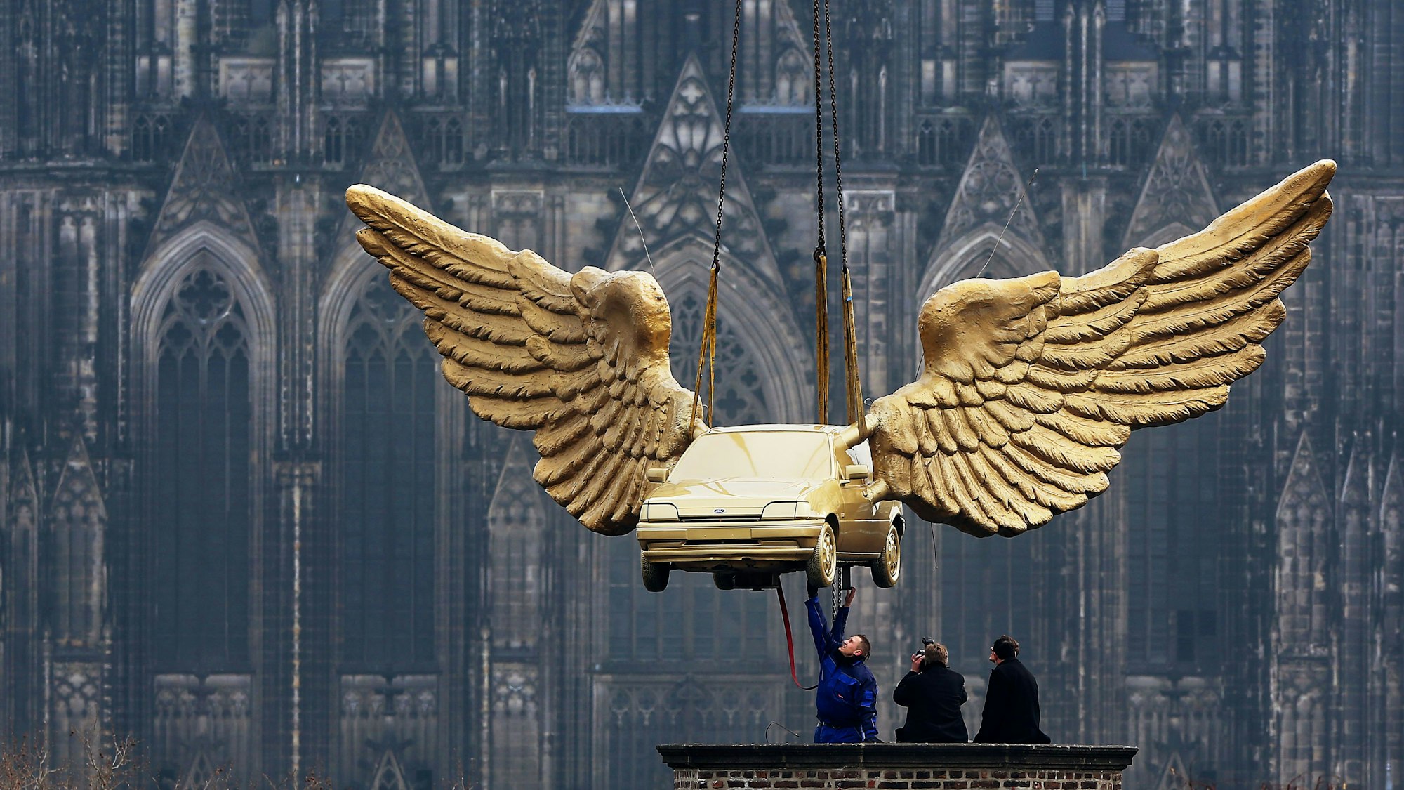 Köln: Arbeiter nehmen auf dem Dach des Kölnischen Stadtmuseums das Flügelauto des Künstlers HA Schult entgegen.