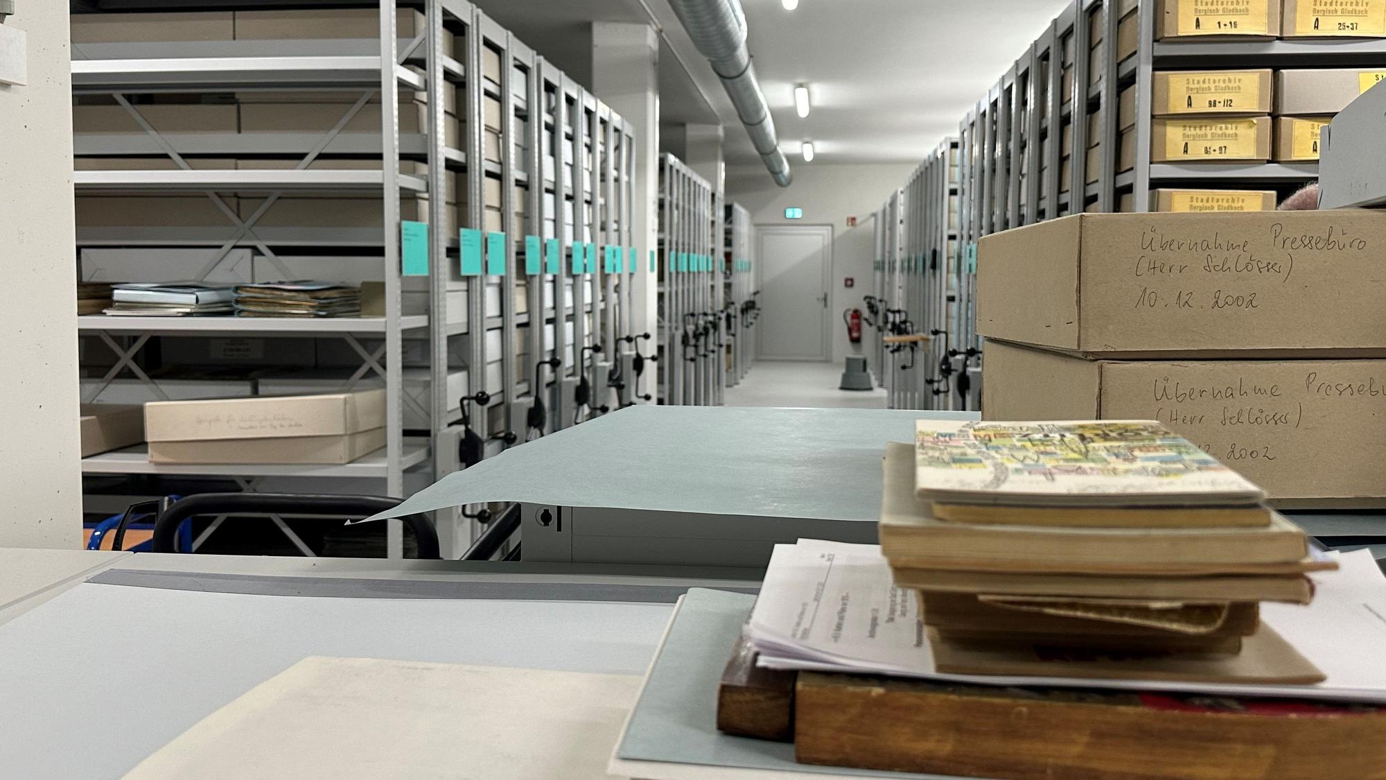 Das Magazin eines Archivs: graue, bewegliche Metallregale, in denen beschriftete Pappkartons liegen