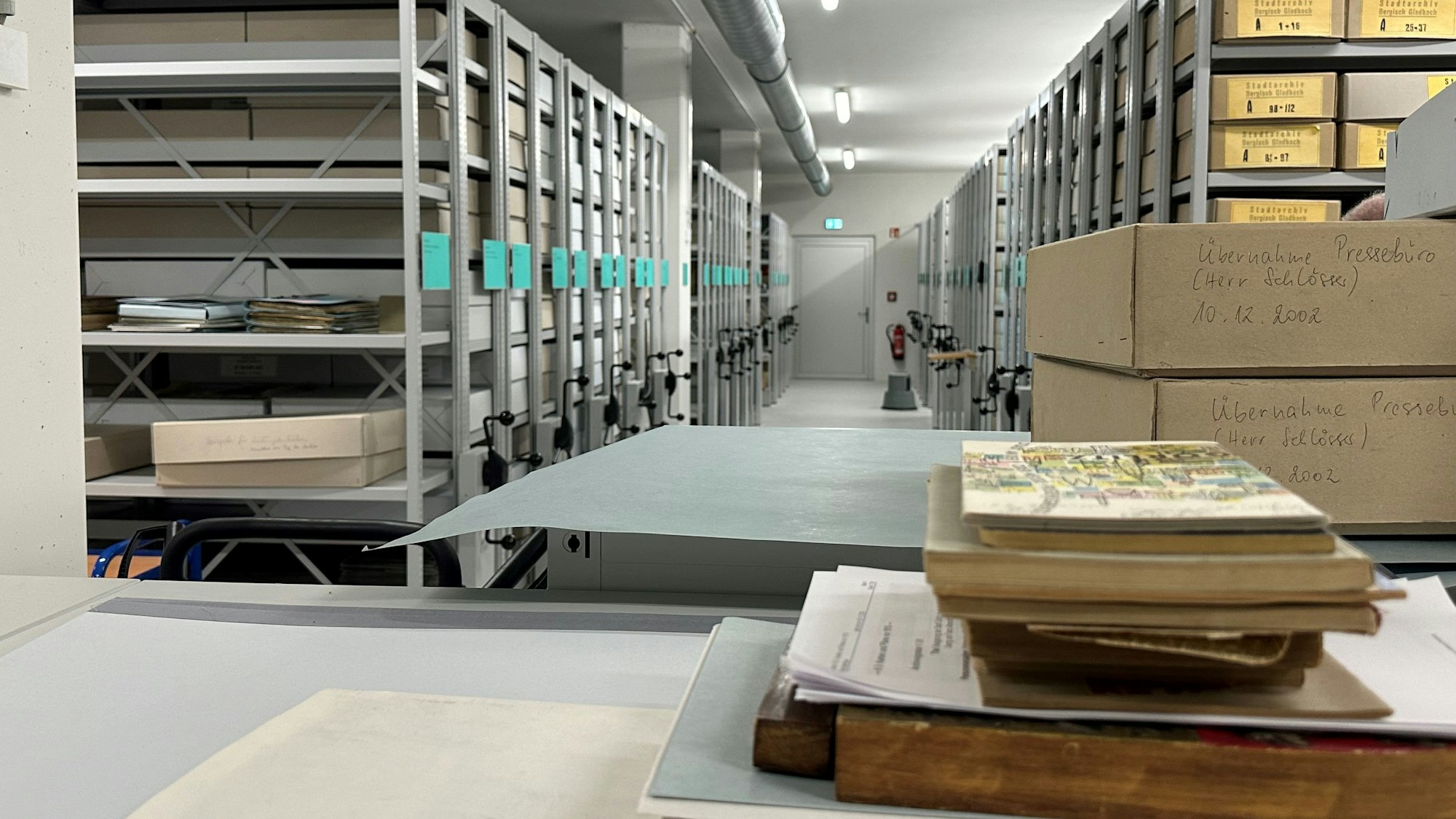 Das Magazin eines Archivs: graue, bewegliche Metallregale, in denen beschriftete Pappkartons liegen