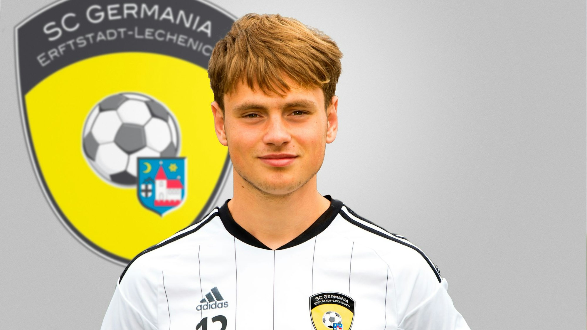 Ein junger Mann steht vor einem Vereinslogo.