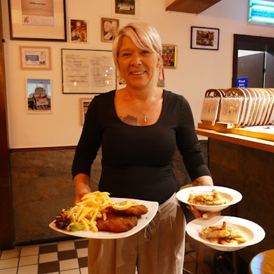 Wirtin Steffi Böckem hält Teller mit deftigem Essen in der Hand.
