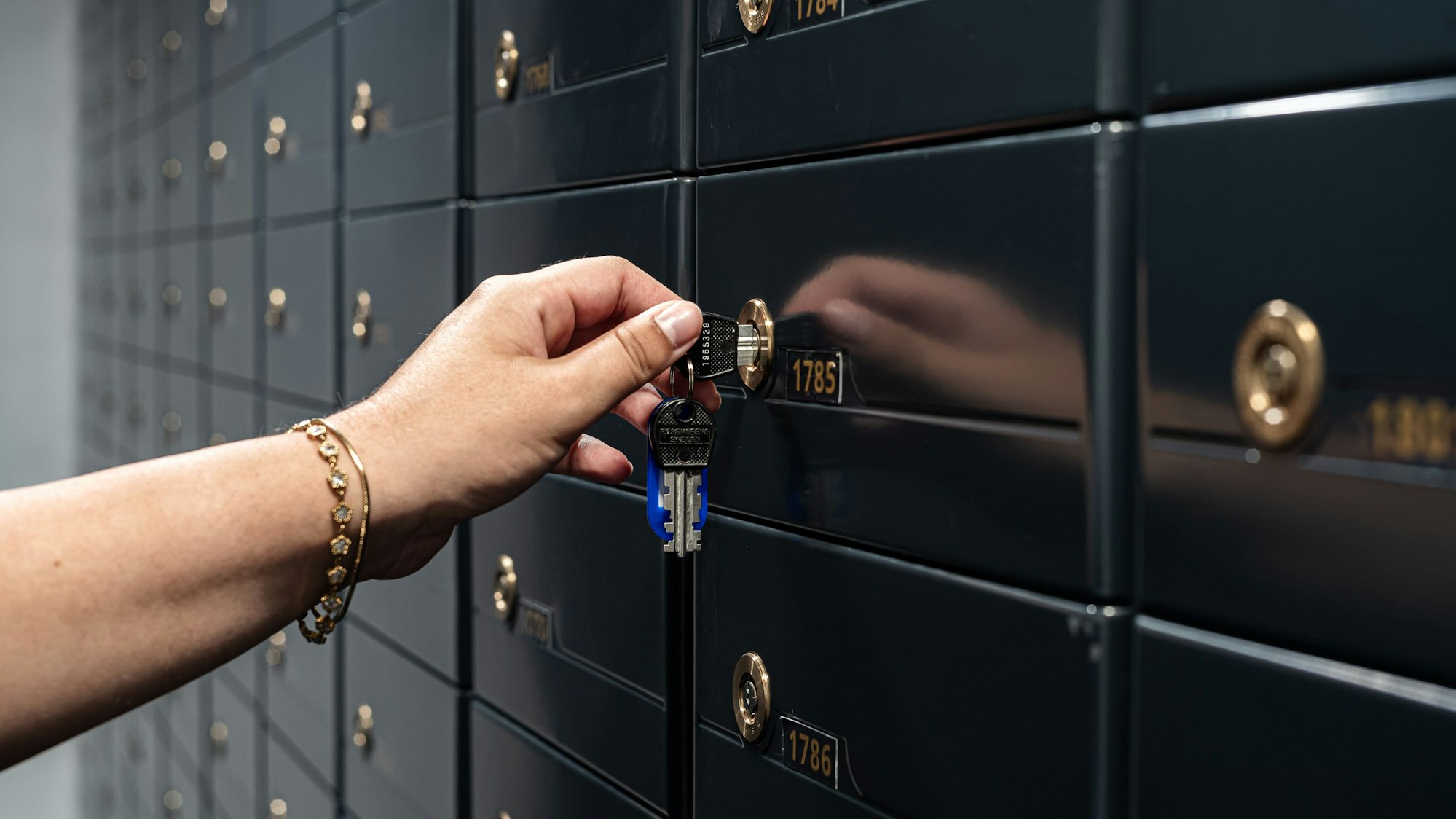 Eine Hand schließt ein Schließfach mit einem Schlüssel ab.