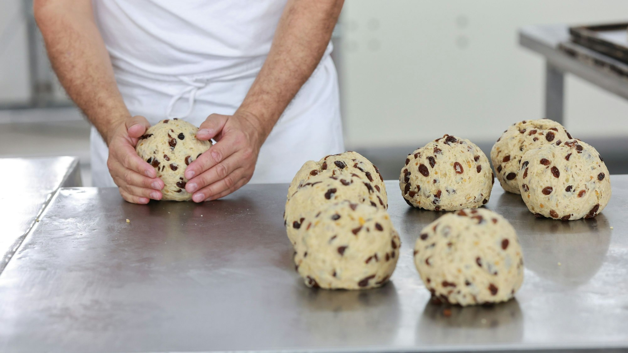 Das Bild zeigt die Hand eines Bäckers, die einen Teigrohling formt.