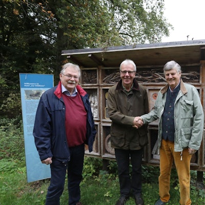 Drei Männer vor einem sogenannten Bienenhotel.