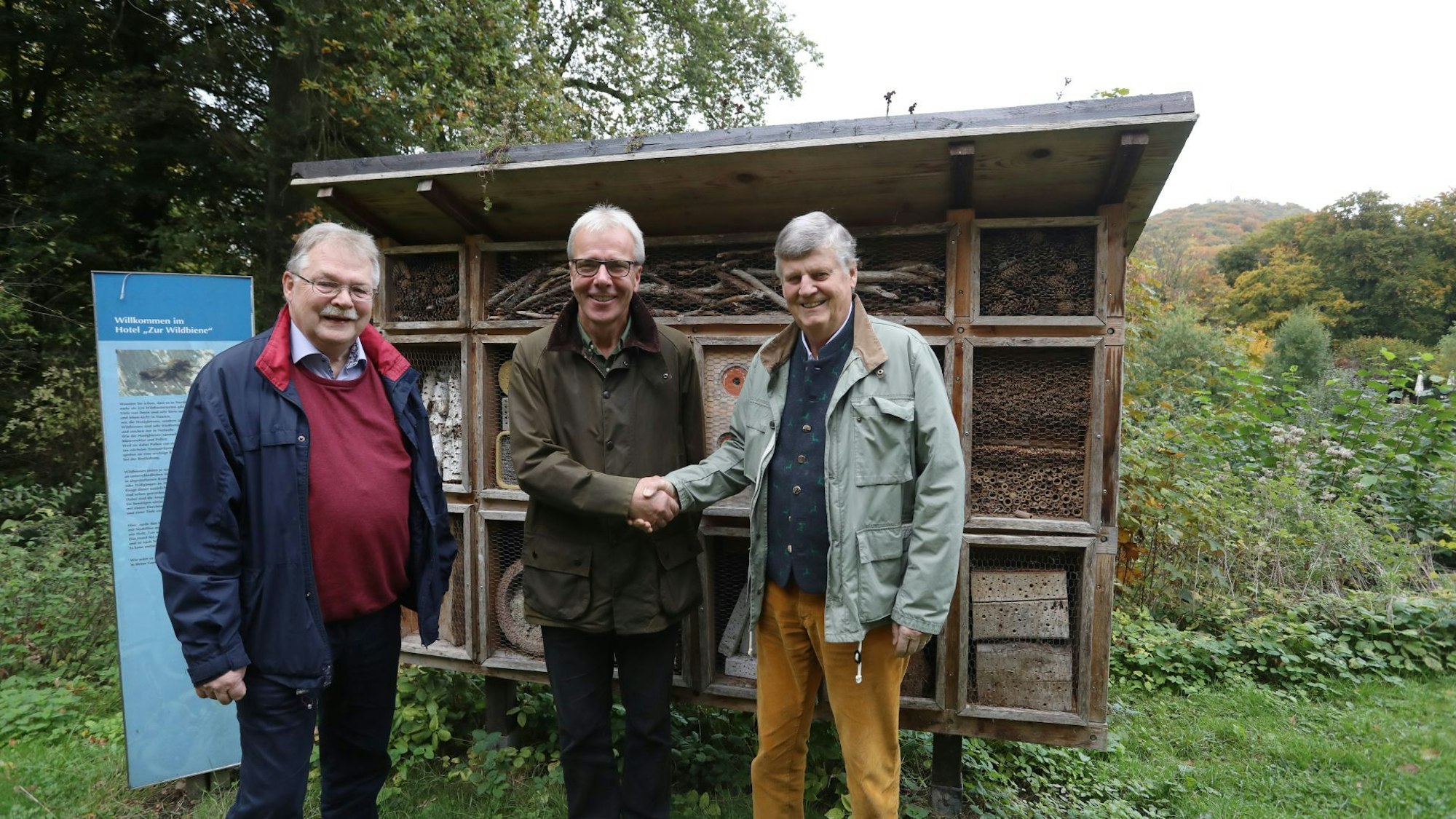 Drei Männer vor einem sogenannten Bienenhotel.
