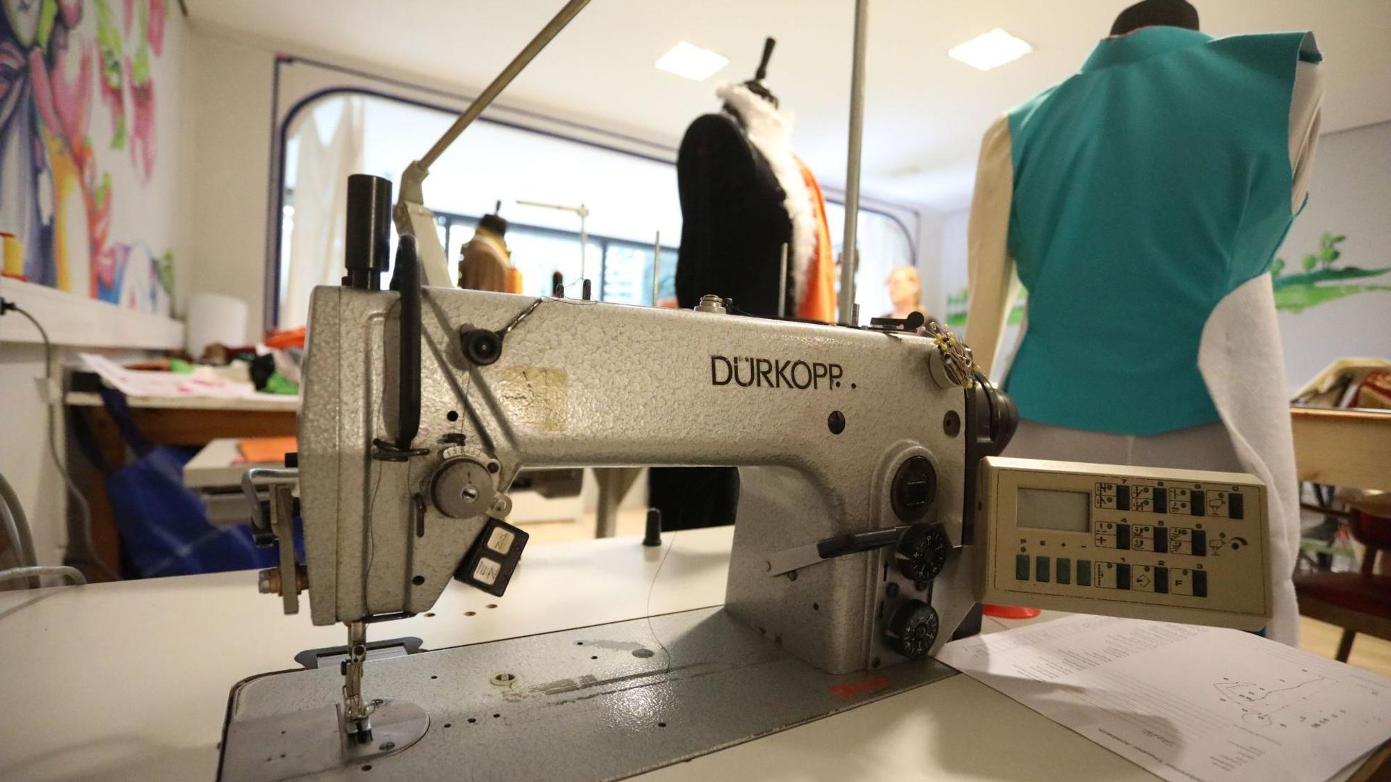 Eine alte Nähmaschine, daneben zwei Kleiderpuppen.