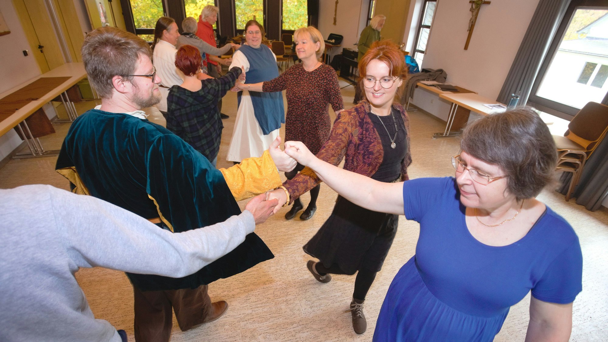Frauen und Männer üben bei einem Tanzkurs Reigentänze aus vergangener Zeit.