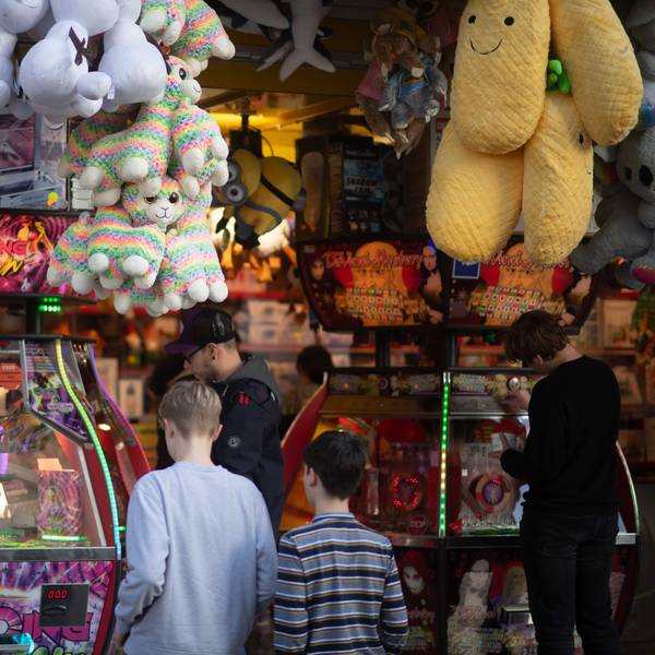 Zwei Kinder stehen vor einem .bunt beleuchteten Kirmesstand