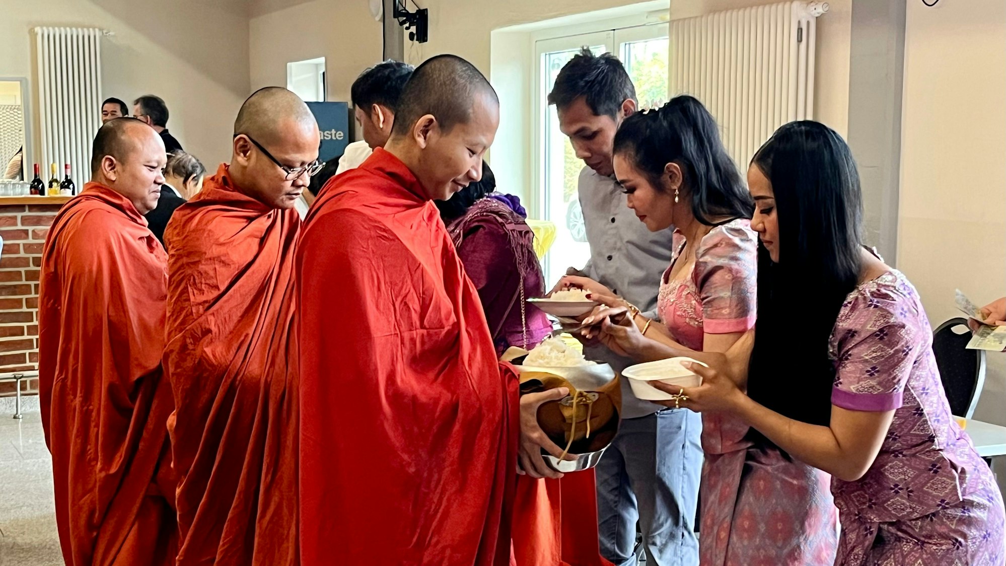 Das Foto zeigt Mönche, die Speisen von Gästen entgegen nehmen.