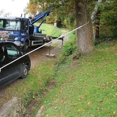 Ein Imker in Schutzanzug hält eine vier Meter lange Lanze mit einem Gift in den Händen.