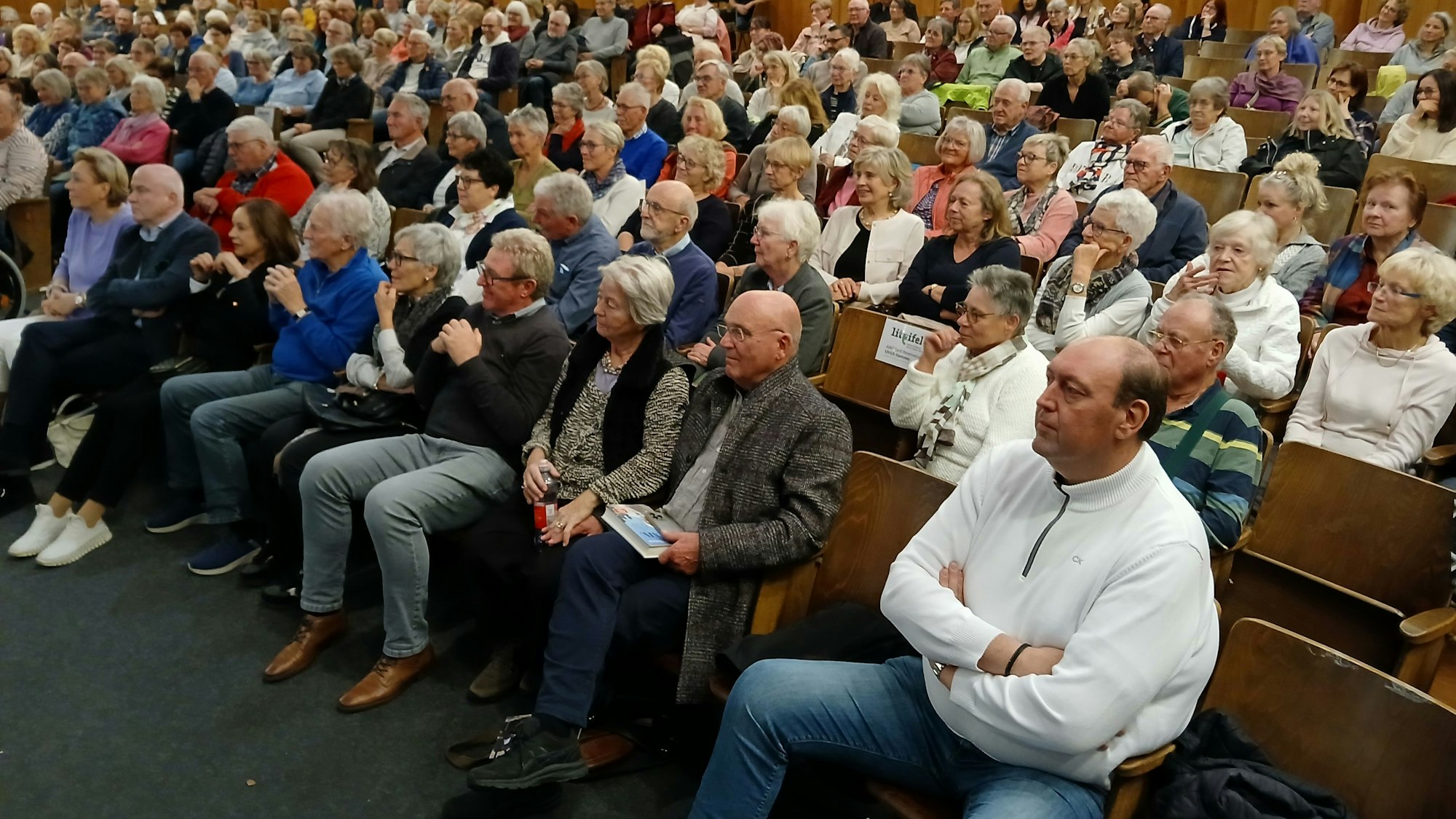 Volle besetzte Stuhlreihen, in denen sichtlich gebannt lauschende Männer und Frauen siitzen.