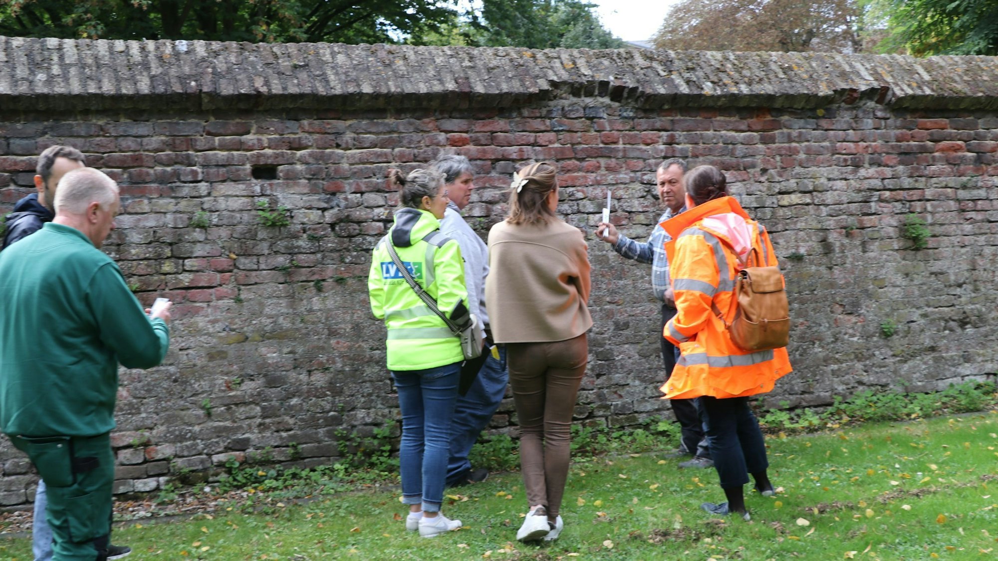 Menschen stehen vor einer Mauer.