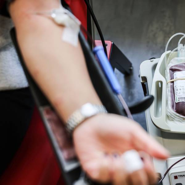 Das Symbolbild Bild zeigt einen Arm mit einer Kanüle in der Vene. Daneben liegt ein Beutel mit Blut.
