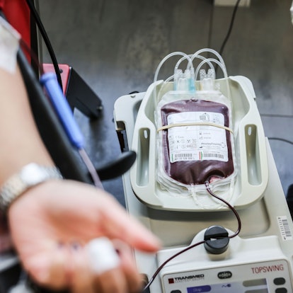 Das Symbolbild Bild zeigt einen Arm mit einer Kanüle in der Vene. Daneben liegt ein Beutel mit Blut.