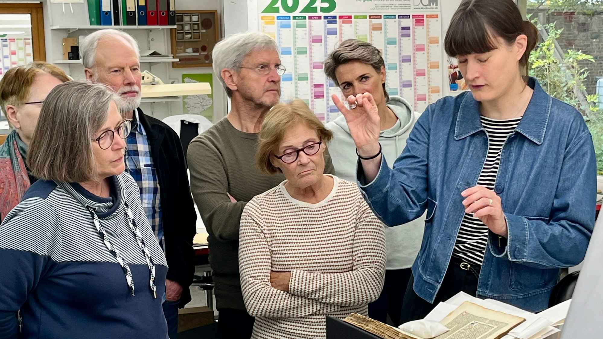 Eine Frau erklärt einer Gruppe von Menschen etwas, dabei gestikuliert sie mit ihren Händen.