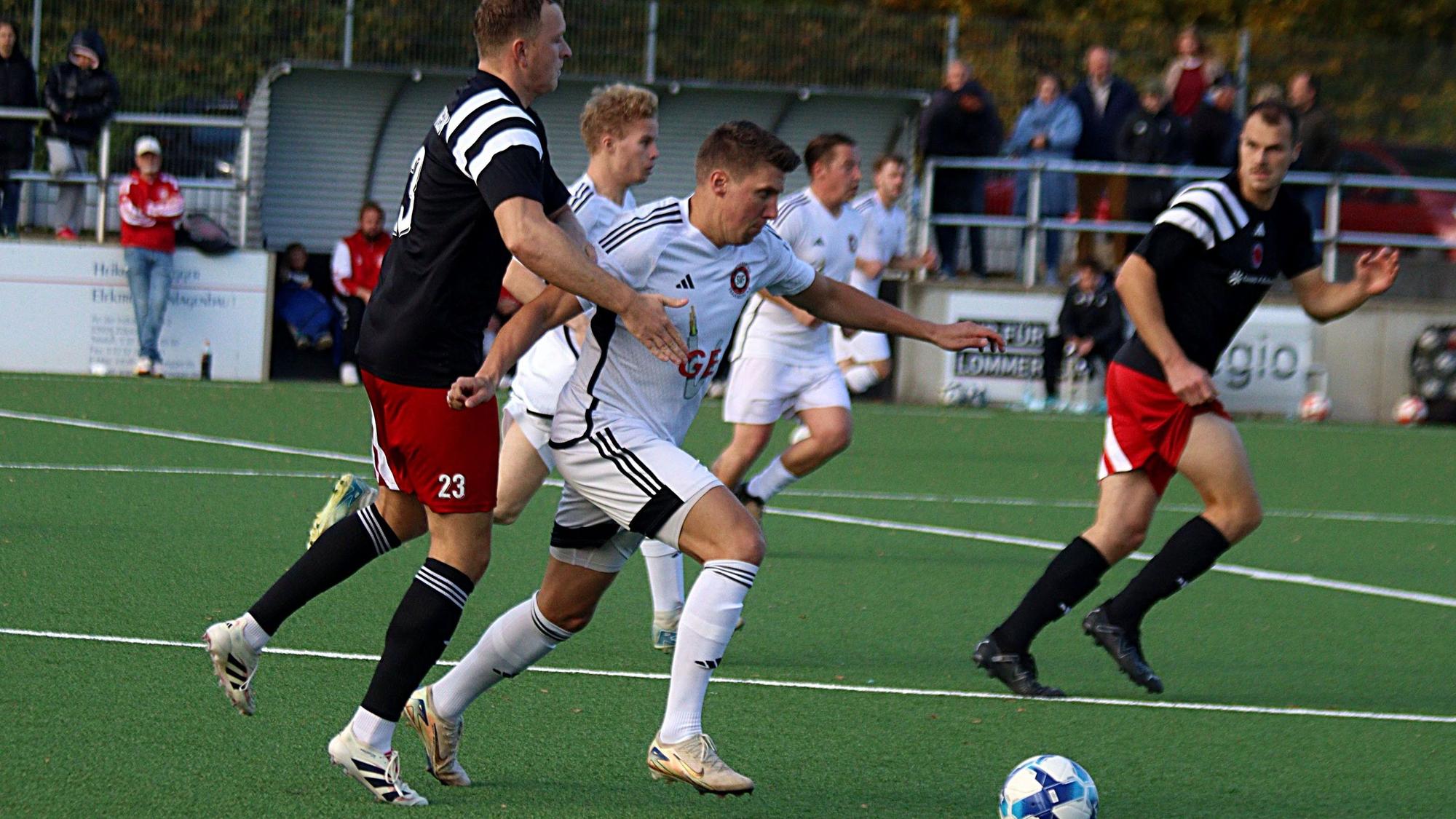 Voller Dynamik läuft Marcel Kaiser mit dem Ball, von hinten versucht Jan-Niklas Runkel den Spieler zu umklammern.
