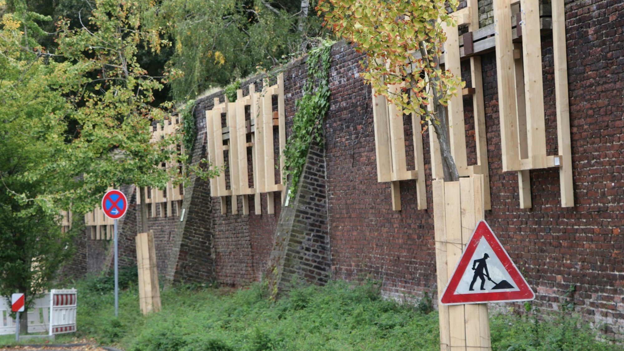 An der Mauer sind Gestelle aus Holz befestigt, sie sichern die Mauer ab.