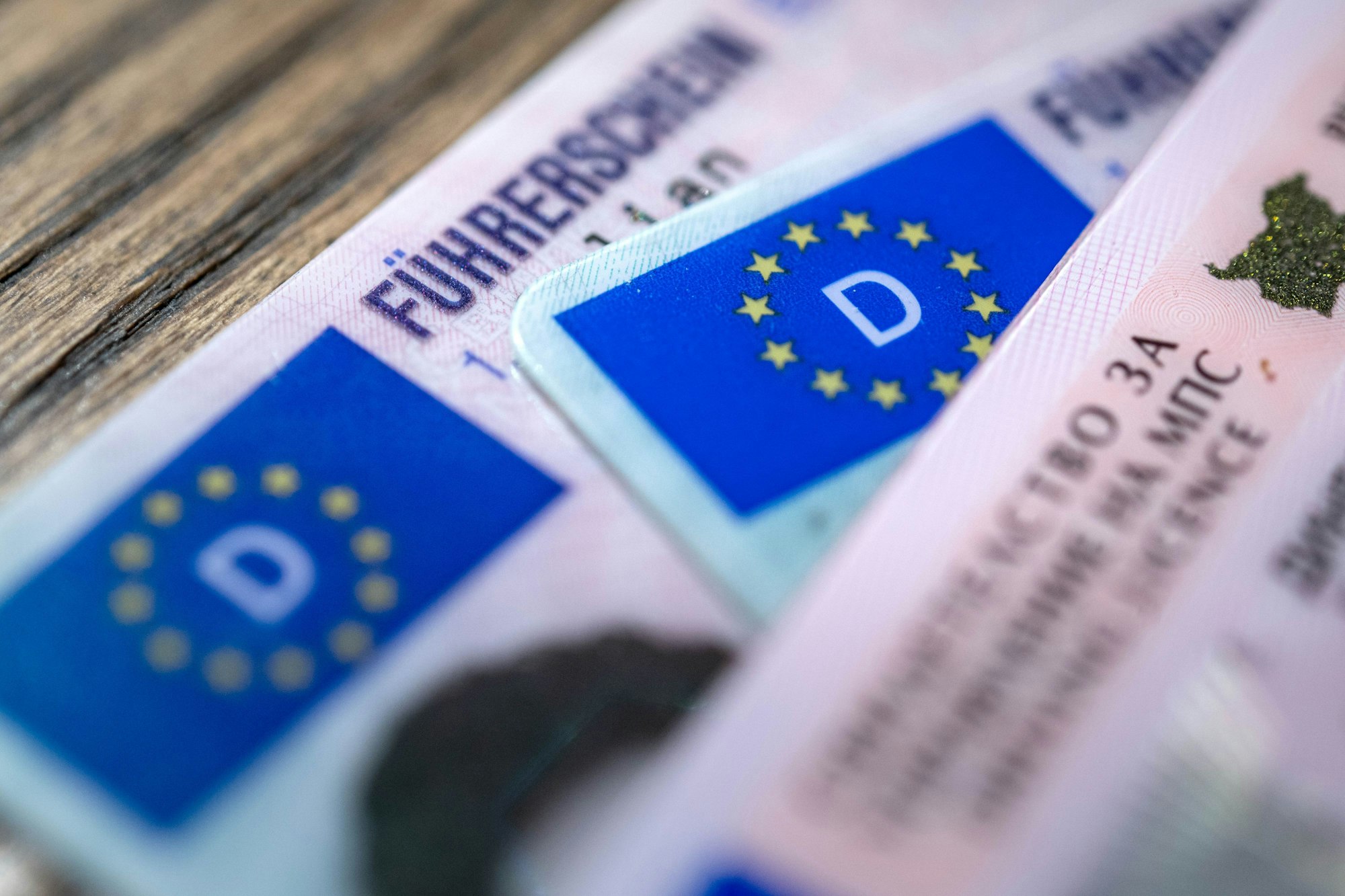 ARCHIV - 06.12.2023, Bremen: ILLUSTRATION - Ein bulgarischer und zwei deutsche Führerscheine liegen auf einem Tisch. Der Verkehrsausschuss im EU-Parlament stimmt über Vorschläge zu neuen EU-Führerscheinregeln ab.