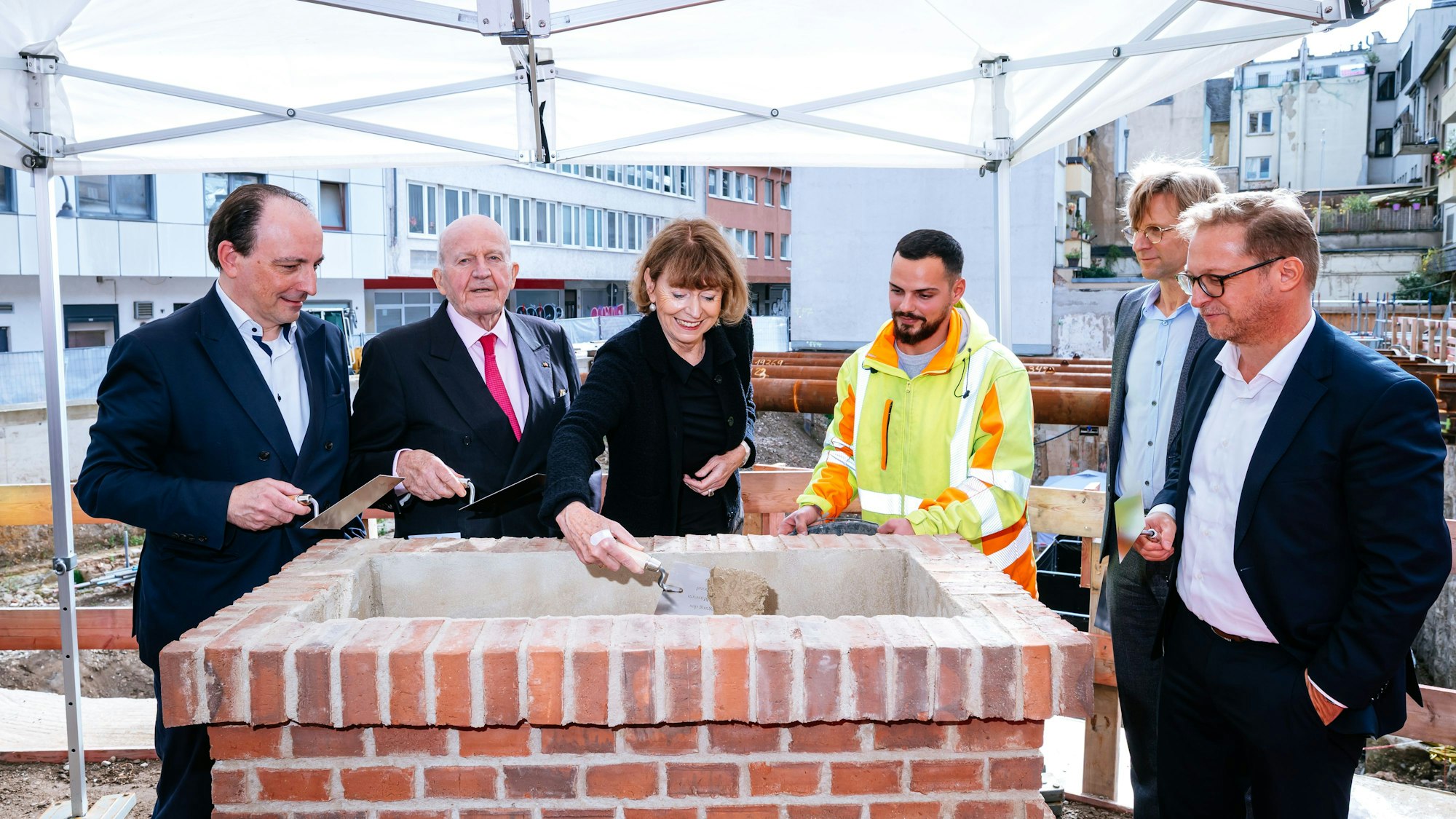 Mit der Maurerkelle legt Henriette Reker den Grundstein für den Erweiterungsbau des Museums Wallraf. An ihrer Seite stehen (v.l.) Marcus Dekiert, Peter Jungen, ein Mitarbeiter von Züblin, Christoph Gantenbein und Jürgen Volm.